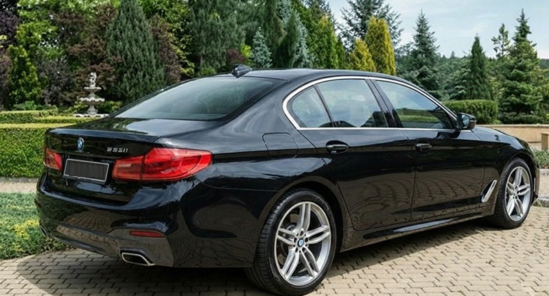 Black BMW 5 Series, rear three-quarter view